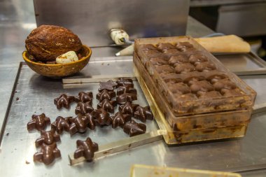 BRÜKSEL, BELGIUM - 1 Ocak 2020: Brüksel, Belçika 'daki çikolata müzesinde kakao çekirdekleri, kakao kabukları ve çikolata kalıplarıyla çikolata sunumu yapan çikolatalı şekerci
