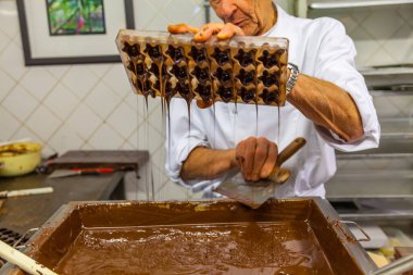 BRÜKSEL, BELGIUM - 1 Ocak 2020: Brüksel, Belçika 'daki çikolata müzesinde kakao çekirdekleri, kakao kabukları ve çikolata kalıplarıyla çikolata sunumu yapan çikolatalı şekerci