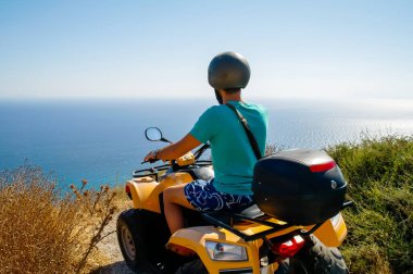 Genç adam plajda motosiklet sürüyor.