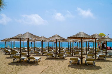 SANTORINI, GREECE - 22 HAZİRAN 2020: Arka planda mavi gökyüzü ve deniz bulunan birkaç plaj şemsiyesi