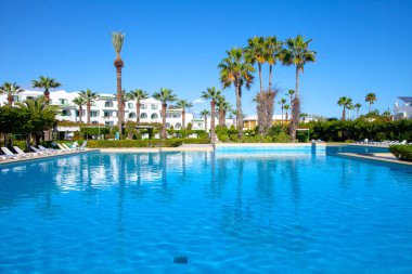 SOUSSE, TUNISIA - 7 HAZİRAN 2020: Sousse otelinde palmiye ağaçları ve bahçeli güzel bir yüzme havuzu