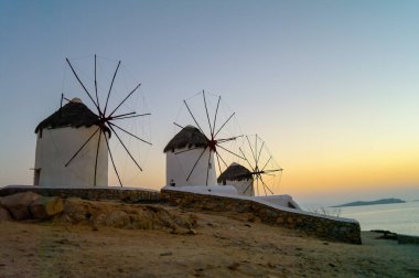 Yunanistan 'da Kiklad' da rüzgar değirmenleri ve sıcak gün batımlarıyla güzel bir akşam manzarası. Tatil ve rahatlama sembolü.