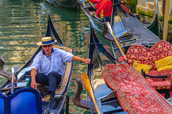 VENICE, ITALY - JANUARY 16, 2020: Gondolas and boats sailing on Venice canals, with tourists and gondoliers with famous Venetian monuments and architecture. Romantic and beautiful city of Venice.