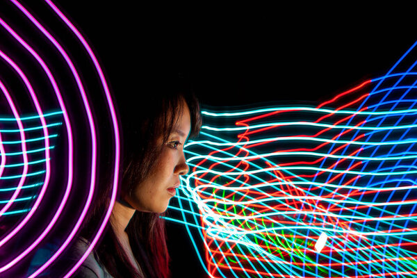 Portrait of woman with led light painting. Creative long exposure photography. Symbol of technology, science, future, energy and speed