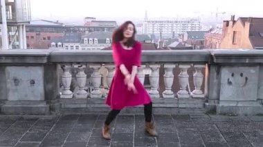 Kırmızı elbiseli genç kadın dans ediyor.