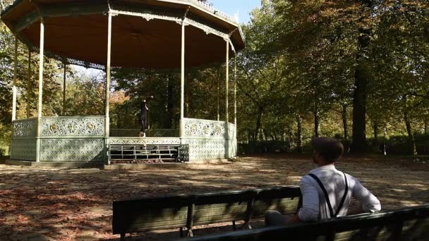 Man Sitting Bench Autumn Park Looking Dancing Woman — Stockvideo