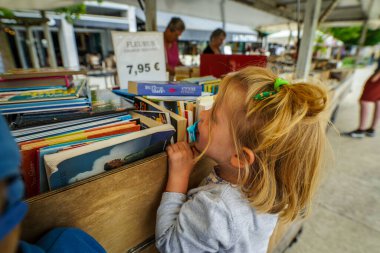 Paris, Fransa - 23 Haziran 2019: Paris, Fransa 'nın merkezindeki bir kitapçıda eski klasik kitap ve roman yığınlarına bakan kız