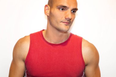 Kırmızı tişörtlü, siyah pantolonlu, elleri kalçasında beyaz tişörtlü genç yakışıklı bir adam.