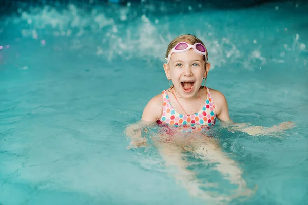 Los niños juegan en el parque acuático. Niños en el parque acuático del parque de atracciones tropical. Niña en la piscina. Niño jugando en el agua. Ropa de baño para niño pequeño . — Foto de Stock