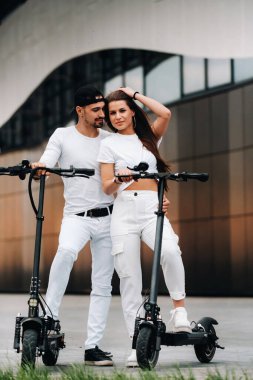 Bir kız ve bir adam şehirde elektrikli scooterlarla dolaşıyorlar. Birbirine aşık bir çift scooterlı..