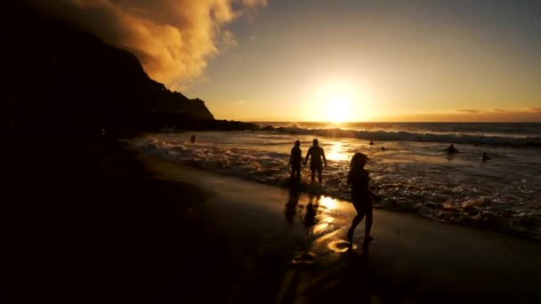 Incrível pôr do sol na ilha de Tenerife no oceano Atlântico, adultos e crianças nadando e brincando no oceano — Vídeo de Stock