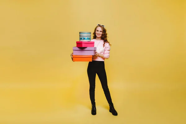 Una joven feliz con cajas de papel coloridas después de comprar aisladas sobre un fondo naranja Studio. Ventas estacionales, compras, gastar dinero en regalos — Foto de Stock