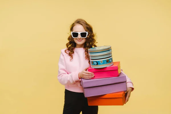 Una joven feliz con cajas de papel coloridas después de comprar aisladas sobre un fondo naranja Studio. Ventas estacionales, compras, gastar dinero en regalos — Foto de Stock