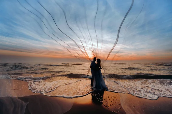 Homem amoroso abraça uma mulher grávida ao pôr do sol, contra o pano de fundo do mar, rio, de pé no cais. Retrato de belos recém-casados esperando um bebê. Fotografia, conceito . — Fotografia de Stock