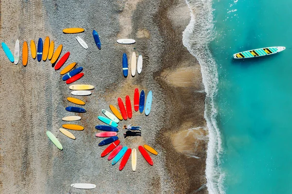 Una hermosa pareja está tumbada en la playa de Francia junto a las tablas de surf, disparando desde un quadcopter, una gran cantidad de tablas de surf están inusualmente tumbados en la playa — Foto de Stock