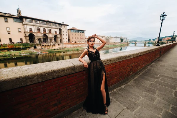 Egy gyönyörű, elegáns menyasszony fekete ruhában végigsétál Firenzén, egy modell fekete ruhában Olaszország óvárosában. — Stock Fotó