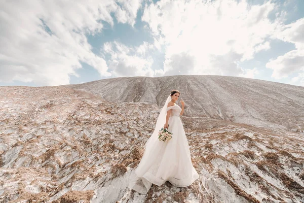 Belle mariée dans une robe de mariée avec un bouquet au sommet des montagnes salées. Une superbe jeune mariée aux cheveux bouclés. Jour du mariage. . Beau portrait de la mariée sans le marié . — Photo