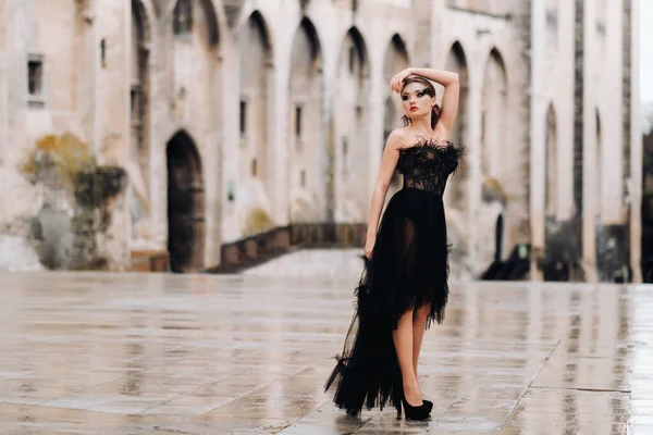 Una sposa elegante in un abito da sposa nero posa nella vecchia città francese di Avignone. Modello in abito nero. Il Palazzo papale di Avignone, Provenza. — Foto Stock