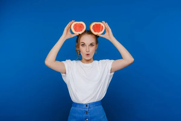 Sorprendido, la muchacha que ríe sostiene el pomelo como orejas. Estilo de vida vegano. Mujer sonriente, concepto de alimentación.Dieta orgánica, pérdida de peso y alimentos saludables. Batidos y zumo fresco. — Foto de Stock