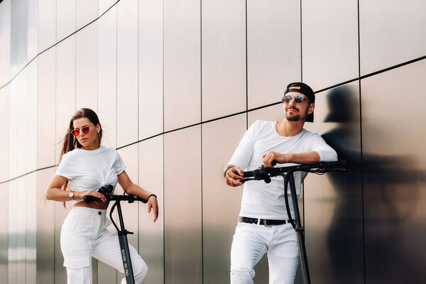 Девушка и парень гуляют на электрических скутерах по городу, влюбленная пара на скутерах