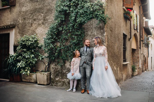 A happy young family walks through the old town of Sirmione in Italy.Stylish family in Italy on a walk.