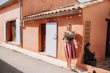 Fransa 'nın kırsalında elinde bir buket çiçekle güzel elbiseli genç bir manken kız. İlkbahar köyünde çiçekli bir kız.