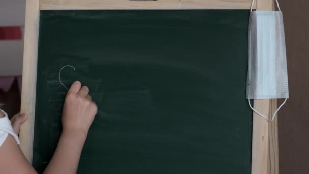 Een Klein Meisje Met Een Masker Schrijft Een Schoolbord Met — Stockvideo