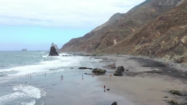 Tenerife, pessoas na praia selvagem de Benijo com areia vulcânica preta. Grandes ondas do oceano Atlântico — Vídeo de Stock