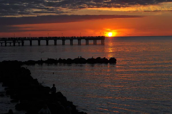 Pessoas Silhueta Cais Madeira Mar Com Belo Pôr Sol Sangrento — Fotografia de Stock