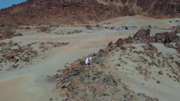 Τενερίφη, σεληνιακό τοπίο στον κρατήρα του ηφαιστείου Τέιντ. Μια γυναίκα κι ένας άντρας με άσπρα ρούχα στέκονται στα βράχια. — Αρχείο Βίντεο
