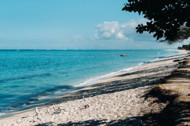Mauritius kıyısında demirli bir tekneyle beyaz sahil ve turkuaz okyanus manzarası..