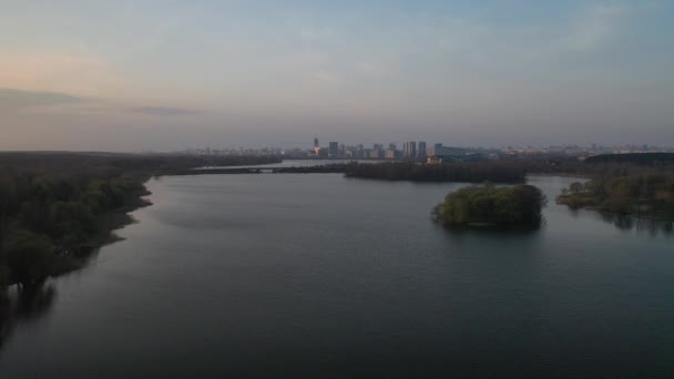 Amanecer desde una altura en el lago detrás del cual la ciudad es visible.Flight por la mañana sobre el río cerca de la ciudad de Minsk — Vídeo de stock