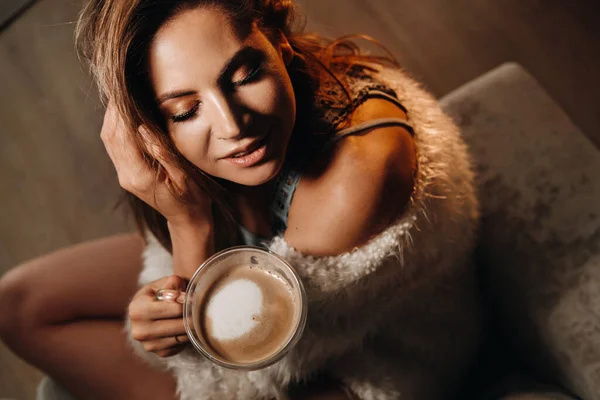 Ontspannen meisje thuis het drinken van koffie.Binnen rust.Het meisje zit comfortabel op de bank en het drinken van koffie — Stockfoto
