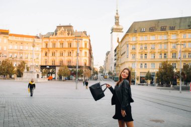 Siyah bir yaz elbisesi ve ceketi içinde genç ve şık bir kız eski şehirde yürüyor. Çek Cumhuriyeti 'nde manken. BRNO.