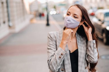 Covid-19 ve Hava kirliliği pm2.5 konsepti. Salgın, sokakta koruyucu maske takan genç bir kadının portresi. Sağlık ve güvenlik kavramını