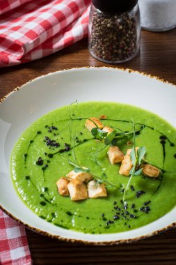 Tofu peynirli brokoli çorbası, yeşil yağ ve bezelye filizi ile süslenmiş. Kapat..