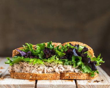 Ton balıklı sandviç ve çavdar ekmeği üzerine marul ahşap zemin üzerinde keten zemin