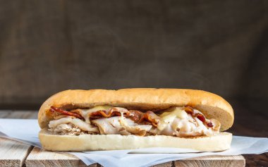 Pastırma ve hindi sandviçi, erimiş peynir ve keten arkaplanlı buhar.