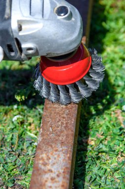  Eski metal bir borudaki pas ve boyayı tel fırçayla sökmek. Yakın plan.