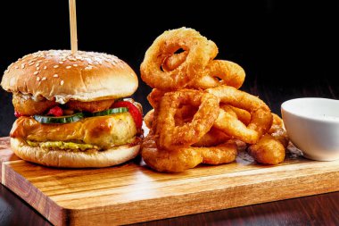 Tahta bir masanın üstünde oturan bir hamburgerin yakın çekimi.