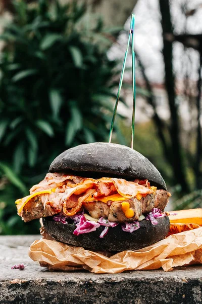 A close up of a steak burger with french fries