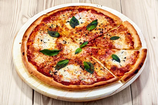 Bir pizza Quattro Formaggio Tahta bir masanın üstünde oturuyor