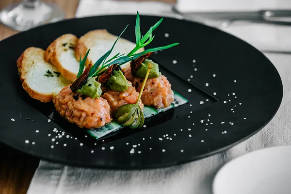 Bir tabak somon tartar ve kızarmış ekmek.
