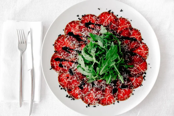 Parmesanlı carpaccio, masanın üstündeki platoda balzamik sirke.