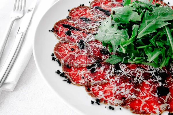 Parmesanlı carpaccio, masada bir platoda balzamik sirke.