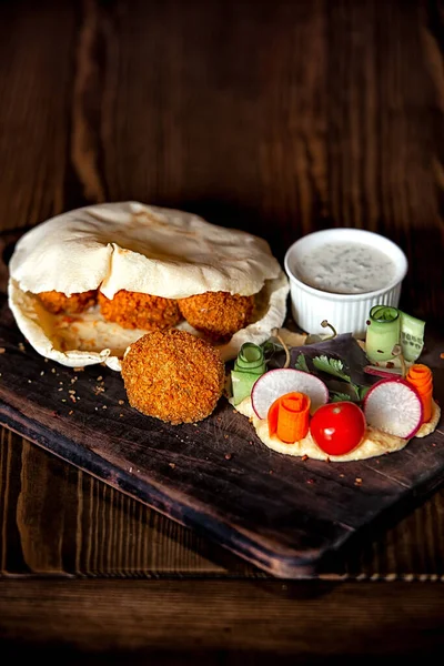 Tahta bir masanın tepesinde pide bir humus ve falafel.