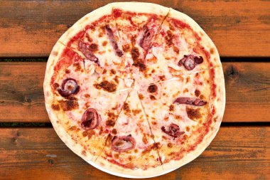 Ahşap bir masanın üstünde marinara pizzası.