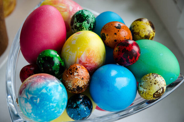 Пасхальные яйца. Красиво окрашенные куриные и перепелиные яйца в хрустальную вазу
