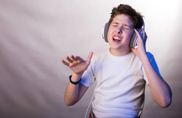 一个年轻人在听他最喜欢的音乐时的情感和喜悦 一个穿着白色T恤 背景为各种浅紫色的年轻人的照片 — 图库照片