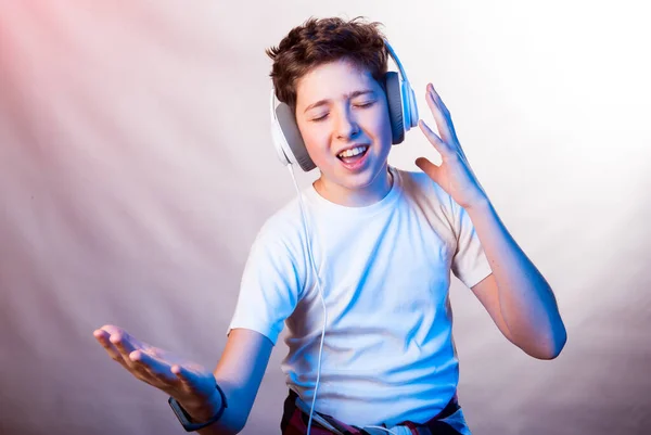 Emotions and joy of a young man while listening to his favorite music. Photo of a young man in a white T-shirt on a background of various light purple shades